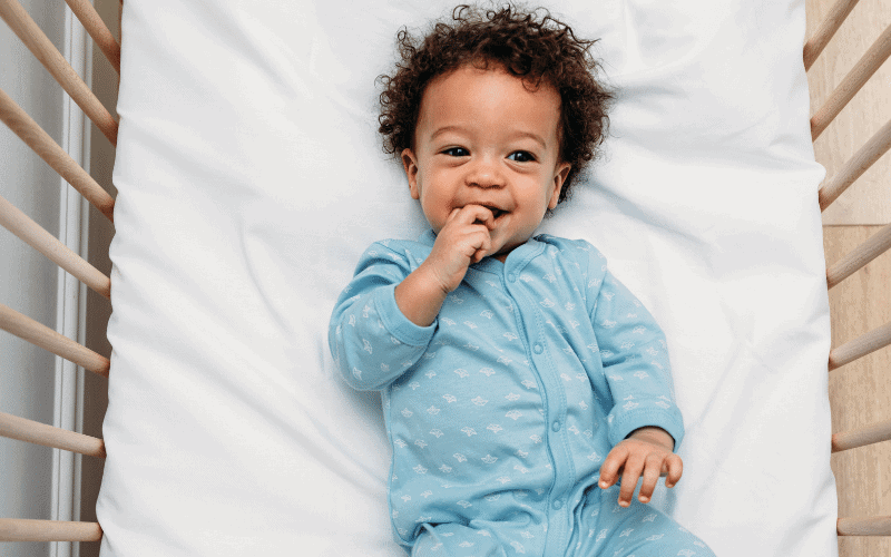 boy in blue pjs in his crib with organic crib sheets