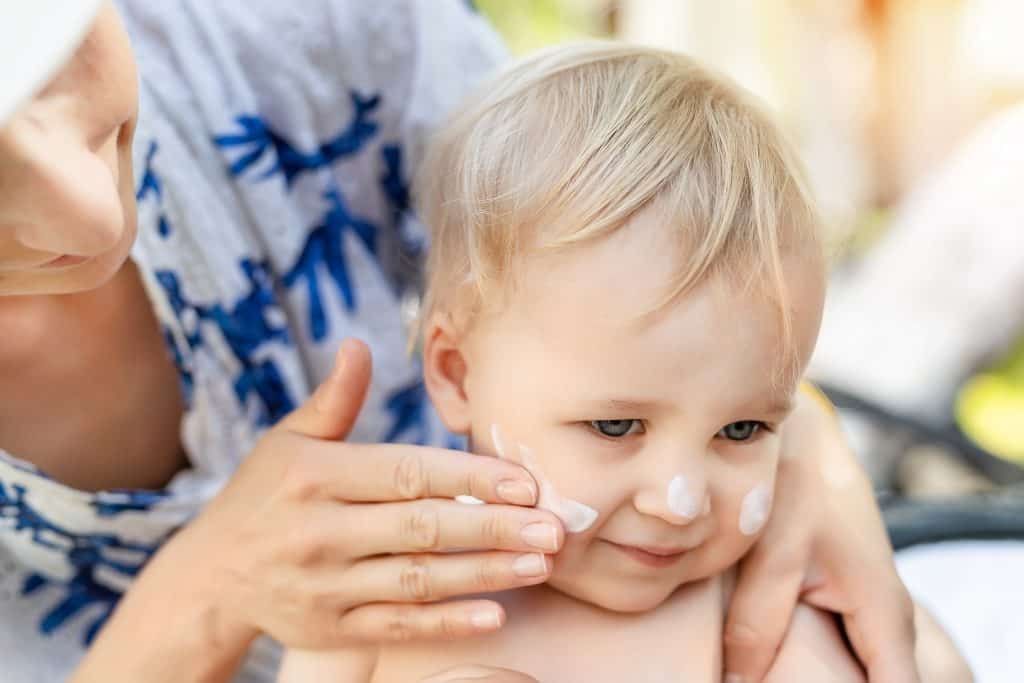 Mom putting non-toxic sunscreen on her child's face.  