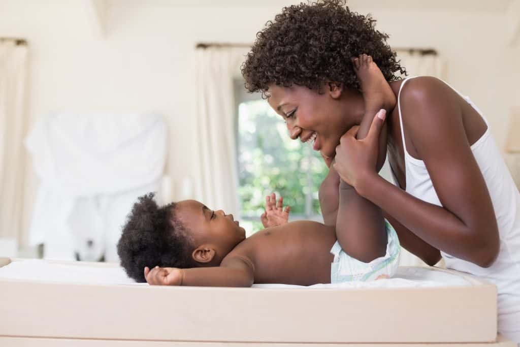 Mom with baby girl on changing table with natural diaper rash cream