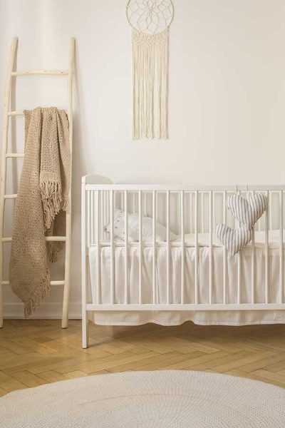 white crib with white organic crib sheets and hearts hanging from outside of crib