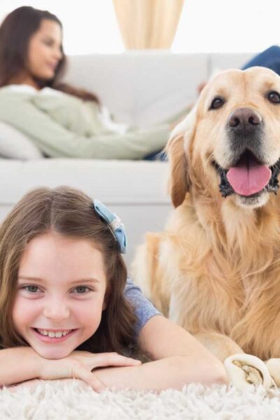 Girl and Dog laying on a rug, mom laying on the couch in the background