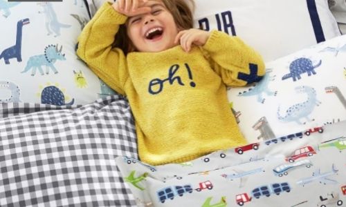 Kid laying in printed bedsheets